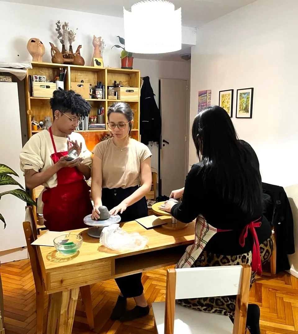 Una clase: tres personas alrededor de una mesa de trabajo, una de ellas en el torno.